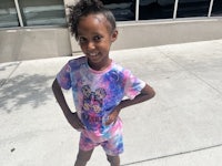 a young girl wearing a tie dye t - shirt and shorts