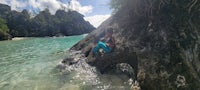 a person is sitting on a rock in the water